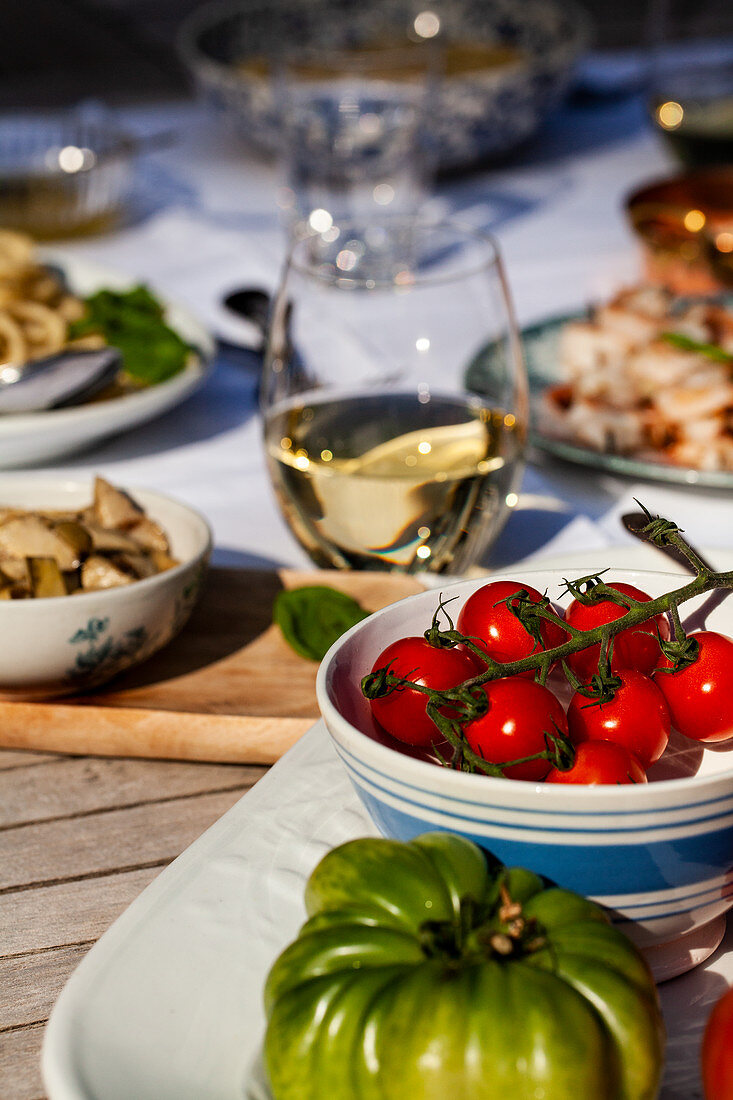 Tomaten, Artischocken und Weißwein auf Tisch im Freien