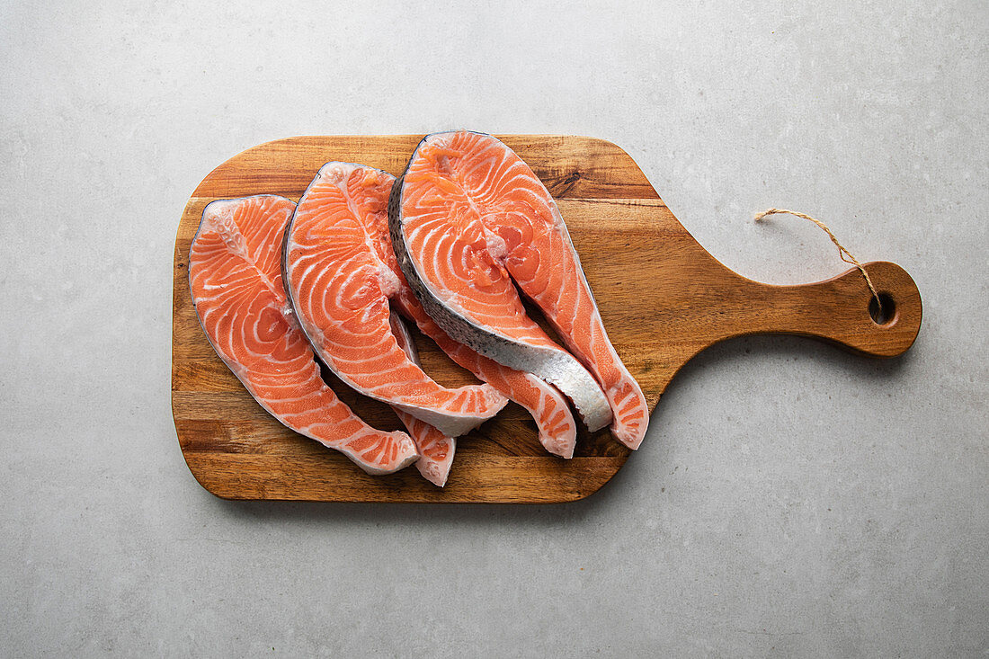 Fresh salmon steaks on wooden board prepared for delicious healthy recipe