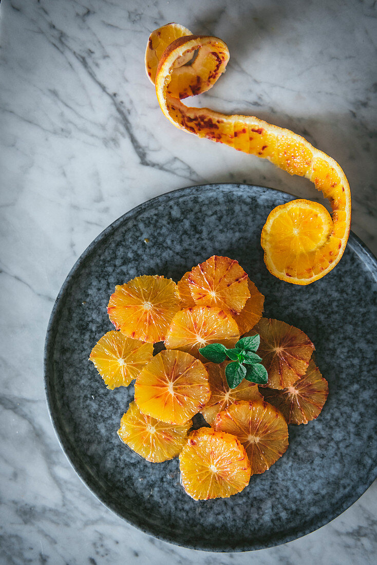 Fresh citrus slices arranged on dish with orange peel on table