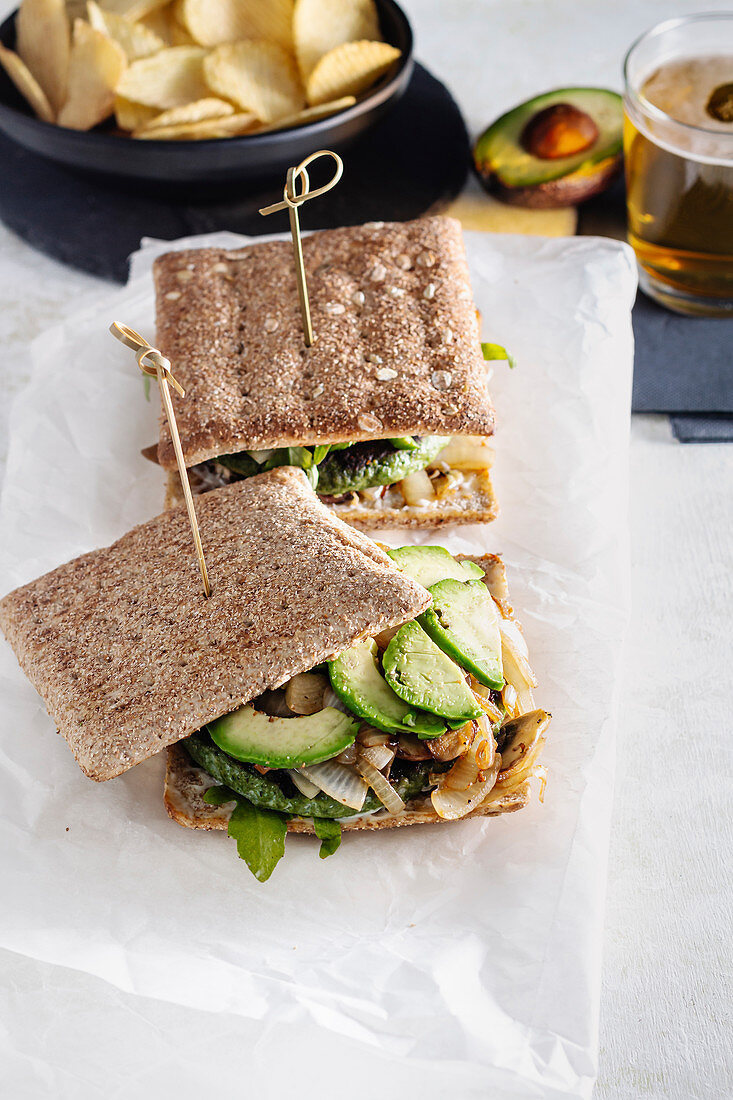 Sandwich mit Avocado, Kartoffelchips und Glas Bier im Café
