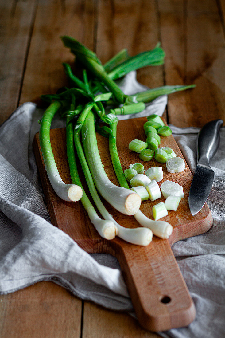 Bunch of ripe scallions placed on wooden cutting board