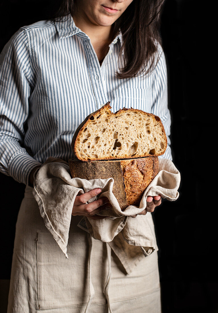 Frau hält halbierten Laib Artisan Brot