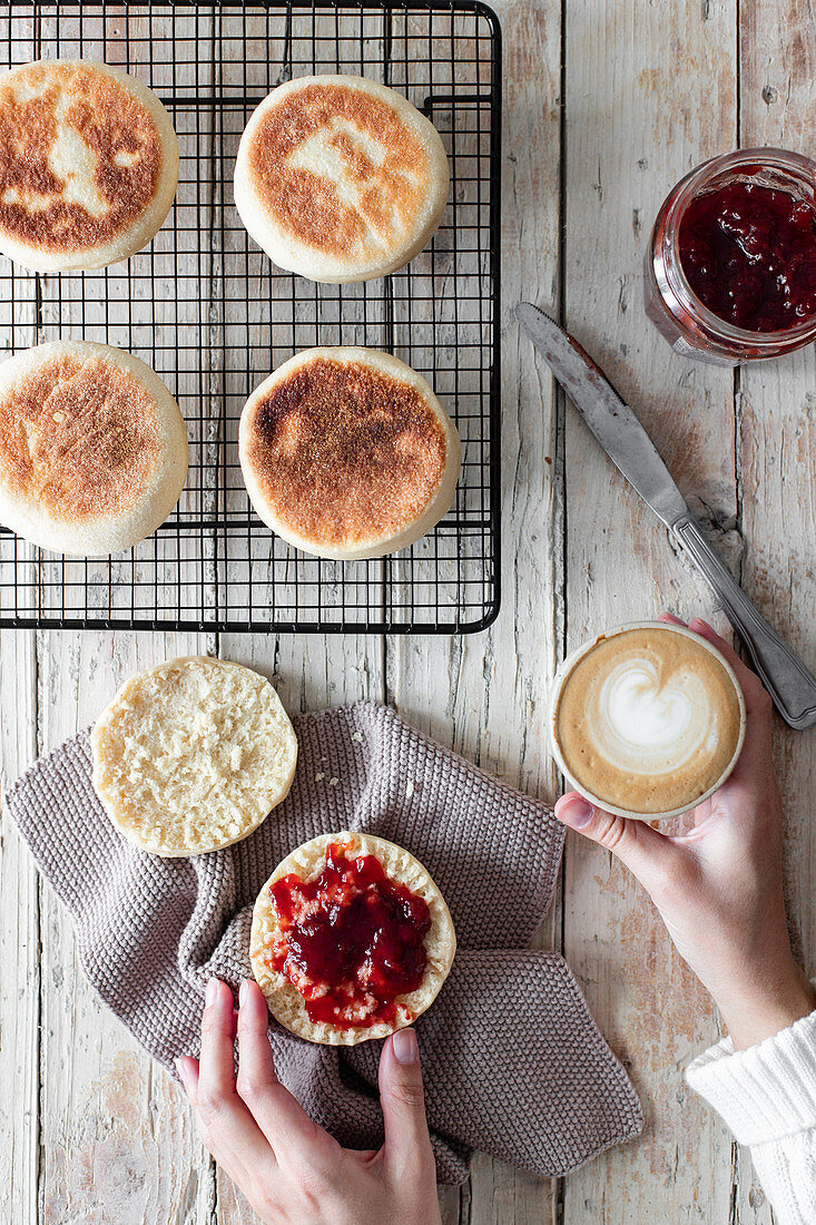 Breakfast at wooden table with cup of cappuccino and fresh homemade buns with berry jam