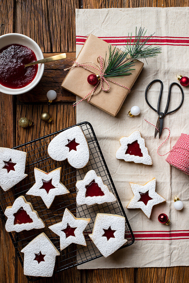 Verschieden geformte Kekse mit roter Beerenmarmelade und Puderzucker zu Weihnachten