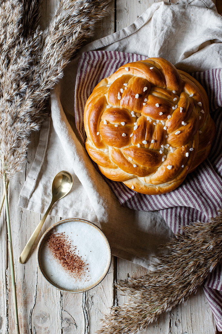 Cup of hot cappuccino with fresh homemade braided bread