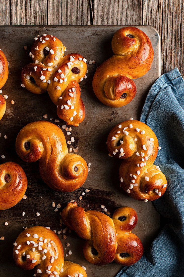 Frisch gebackene Brötchen mit Rosinen und Hagelzucker auf Holztisch