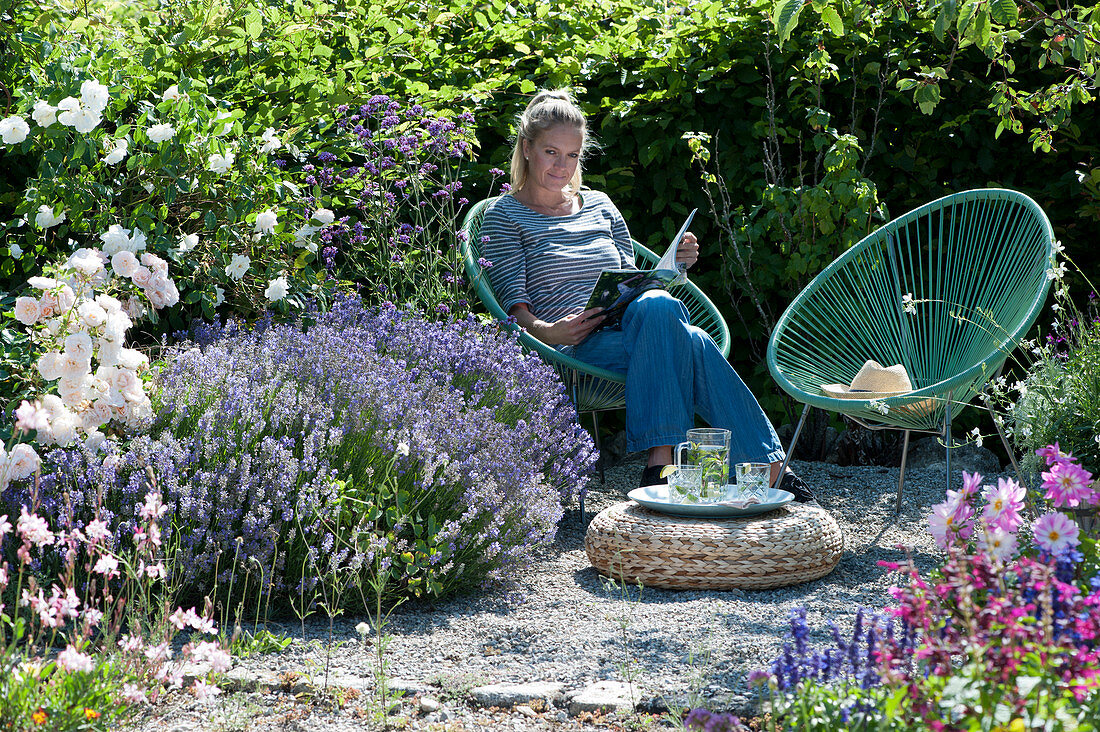 Woman relaxes in the garden next to lavender and roses