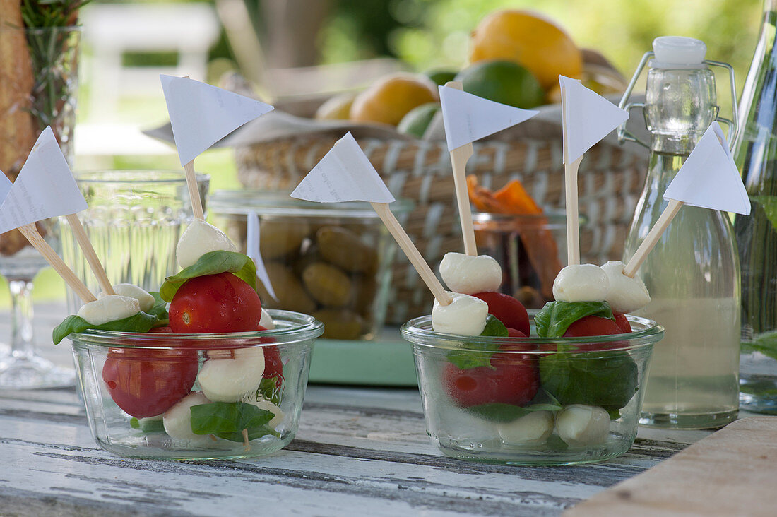 Mozzarella tomato skewers in glasses, bottle with elderflower syrup