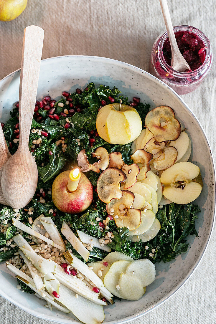 Winter salad with kale, apples, pomegranate seeds and a candle