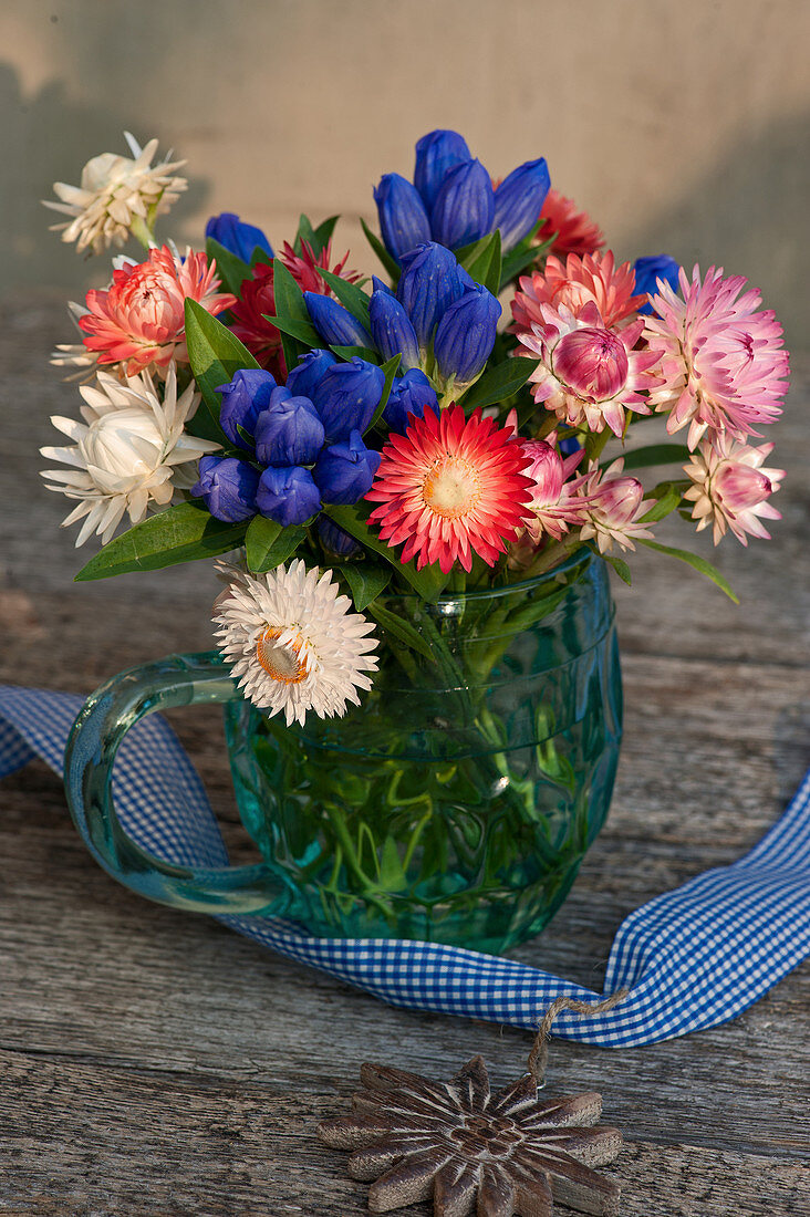 Closed Gentiana with strawflowers in a mug