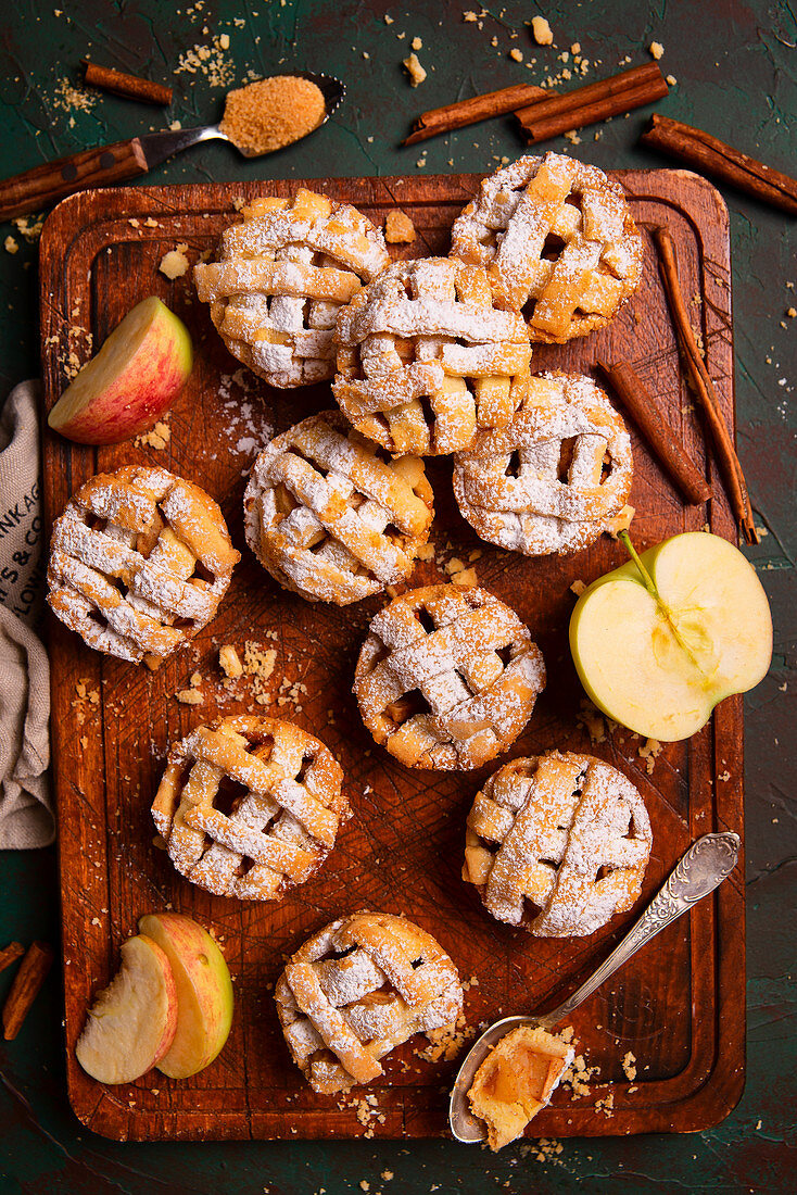 Mini-Applepies mit Zimt und Puderzucker auf Holzbrett