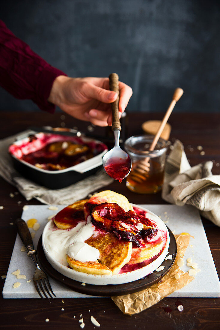 Pancakes with yoghurt baked plums topped with a spoonful of fruit sauce