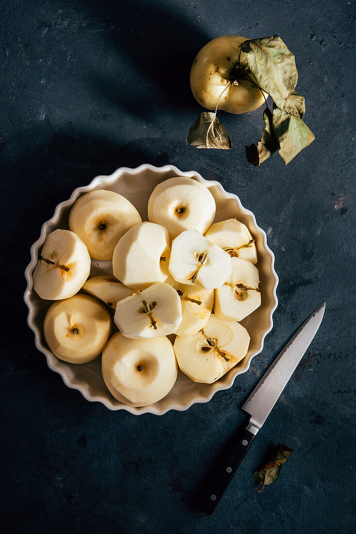 Geschälte und halbierte Äpfel in weißer Schale
