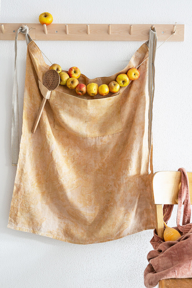 Apron and garland of apples hanging from coat pegs