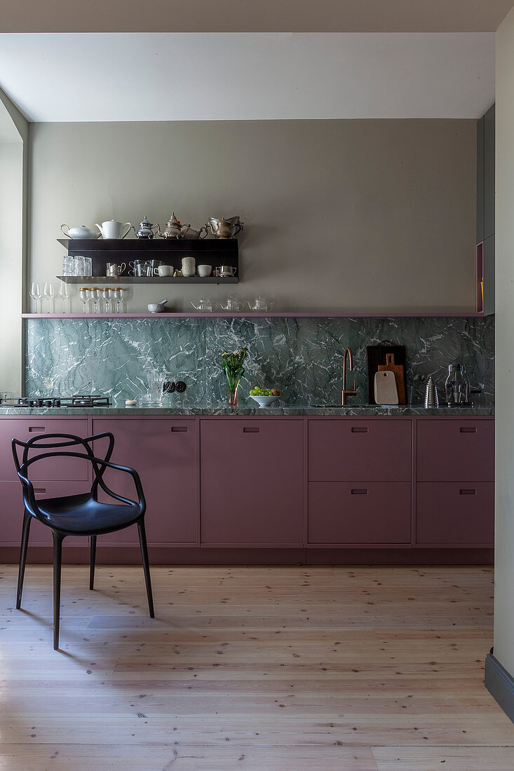 Black chair next to kitchen counter with berry-coloured cabinets