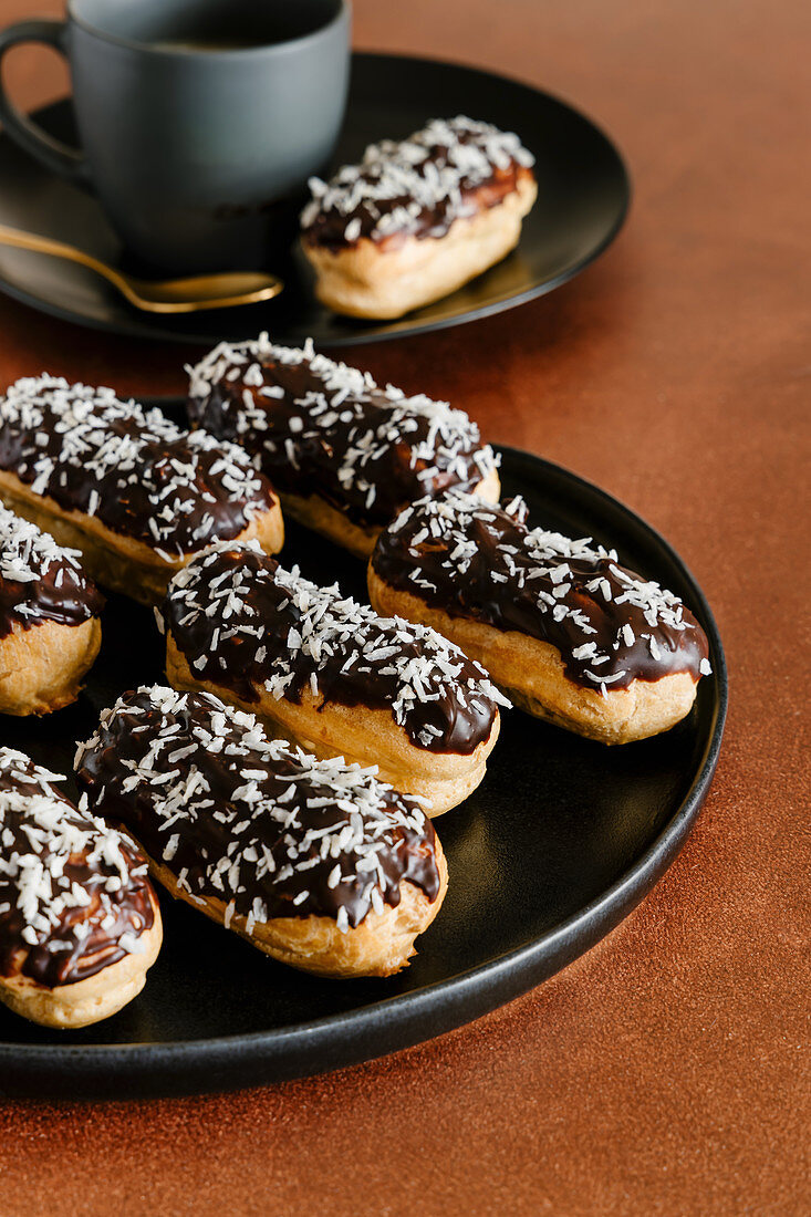 Coconut and chocolate eclairs and cup of coffee