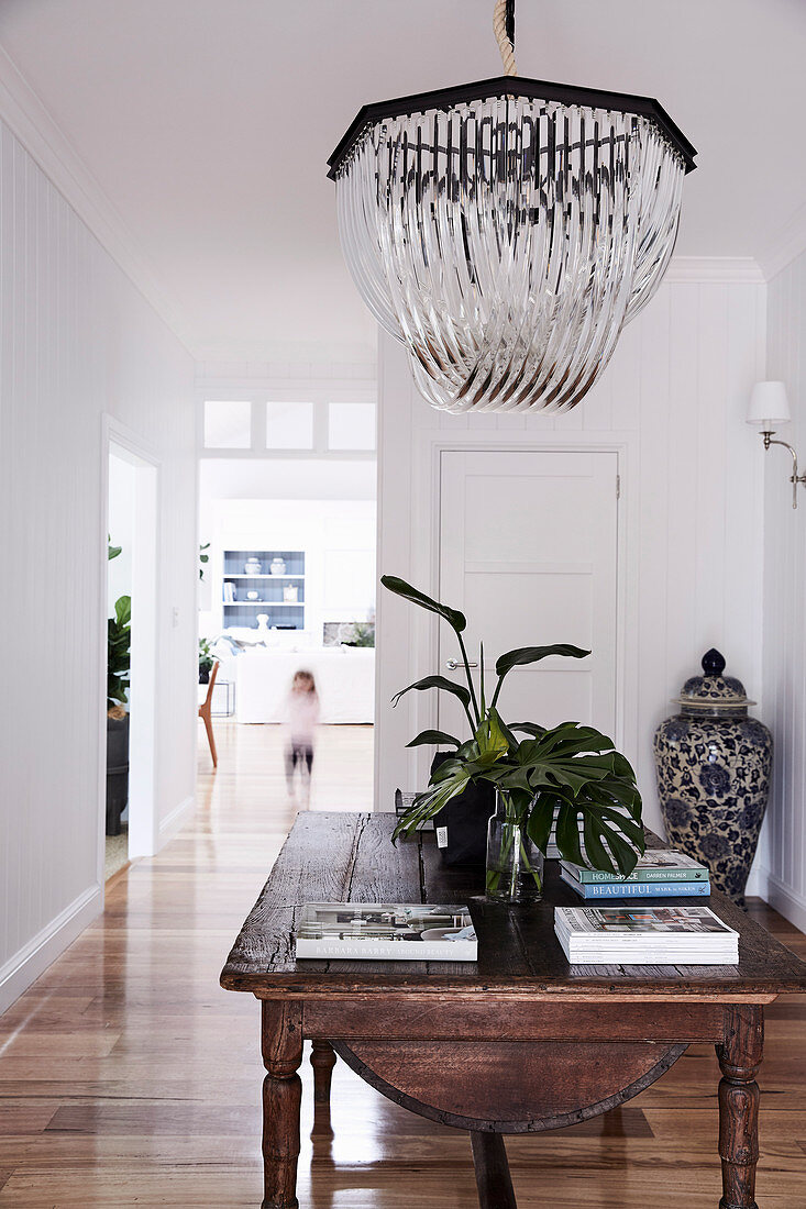 Rustic wooden table with crystal chandelier above in the entrance area