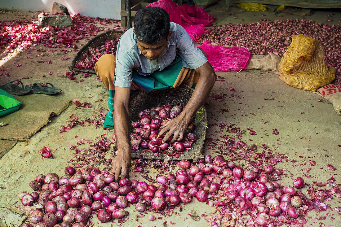 A vendor selling red onions at a market in Sri Lanka