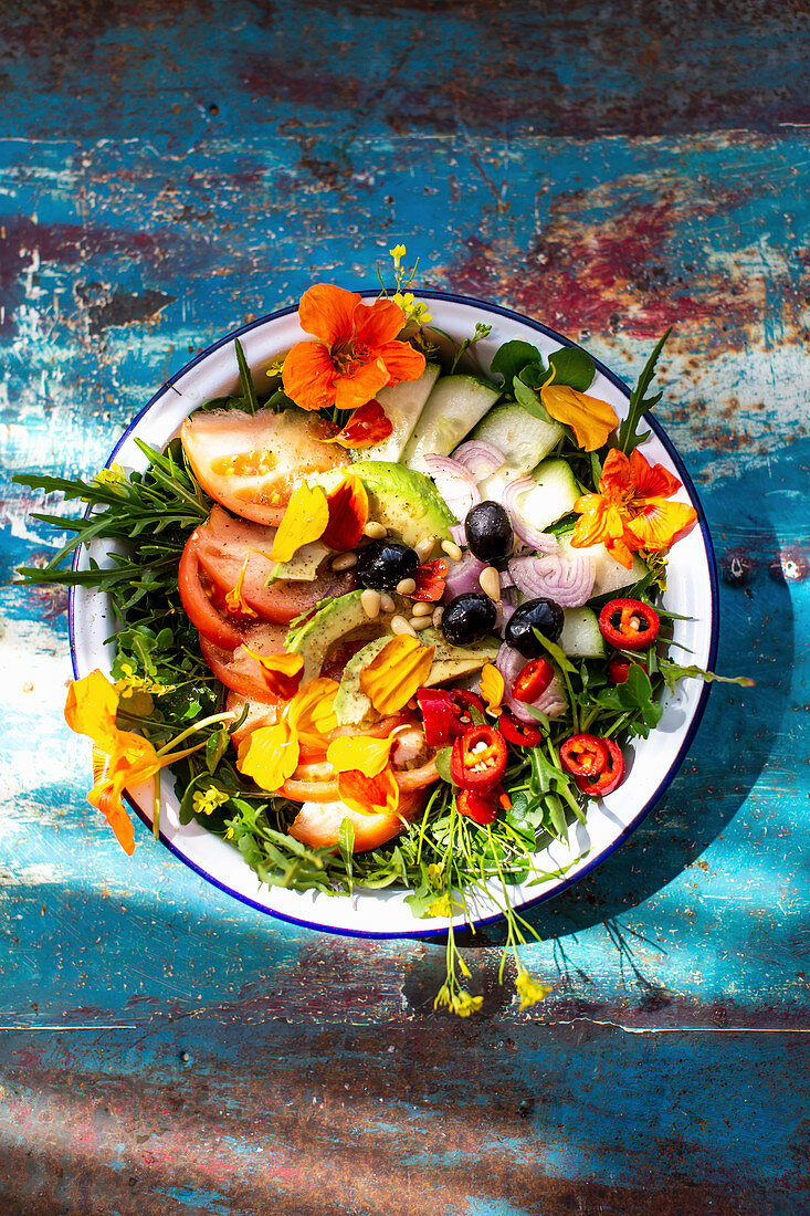Summer salad with tomatoes, cucumber, chilli, olives and edible flowers