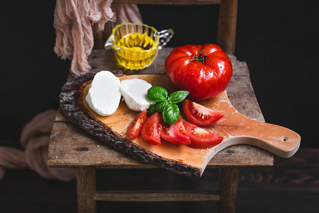 Mozzarella, Tomaten und Basilikum auf rustikalem Holzbrett