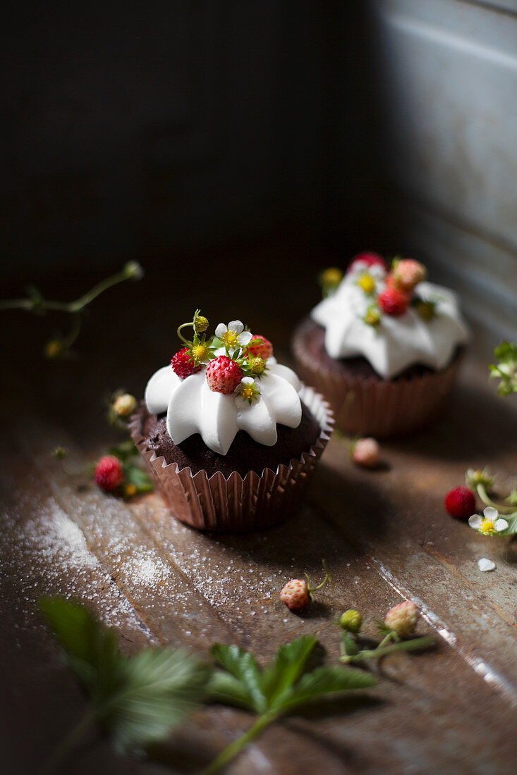 Zwei Schokoladencupcakes mit Sahne und Walderdbeeren