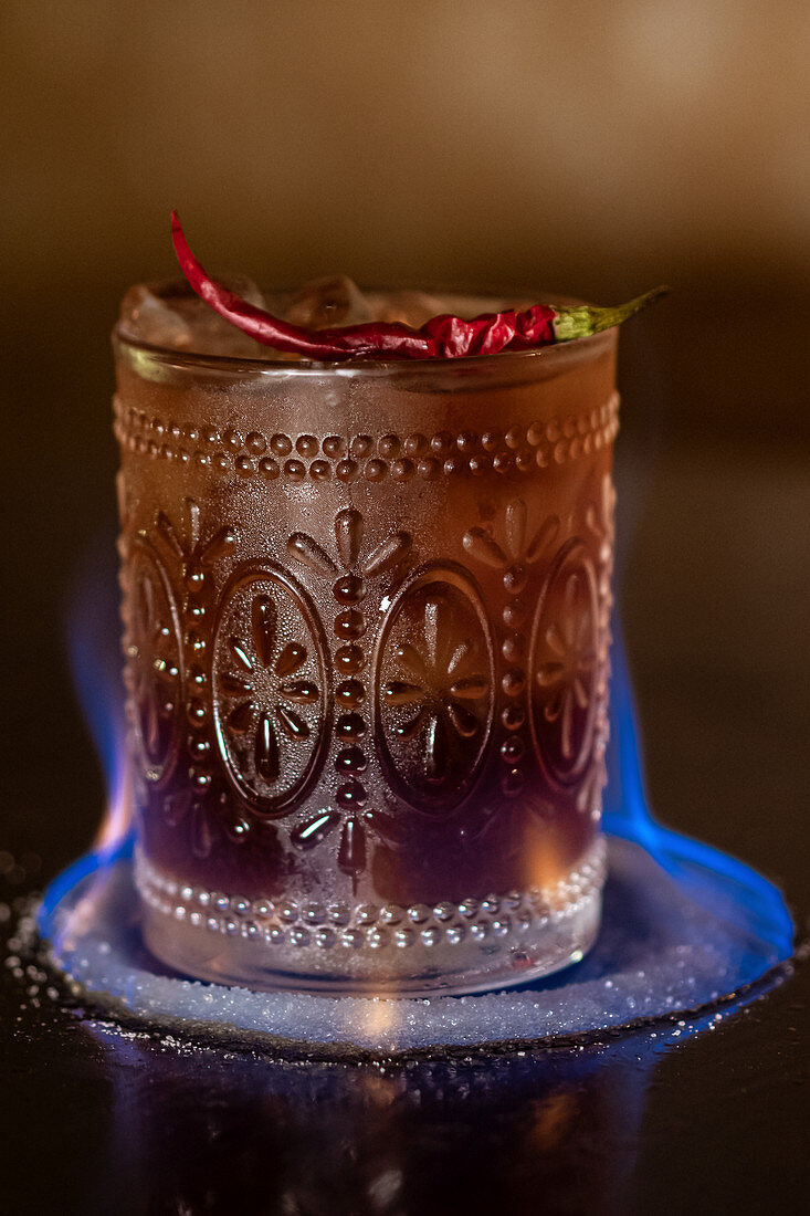 Cocktail mit Eiswürfeln und Chilischote flambieren