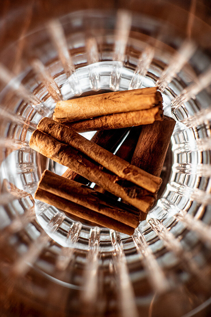 Top view of pile of aromatic cinnamon sticks placed inside glass cup in bar