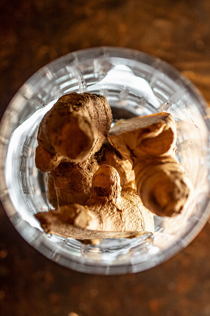 Fresh ginger roots placed inside glass cup on table in bar