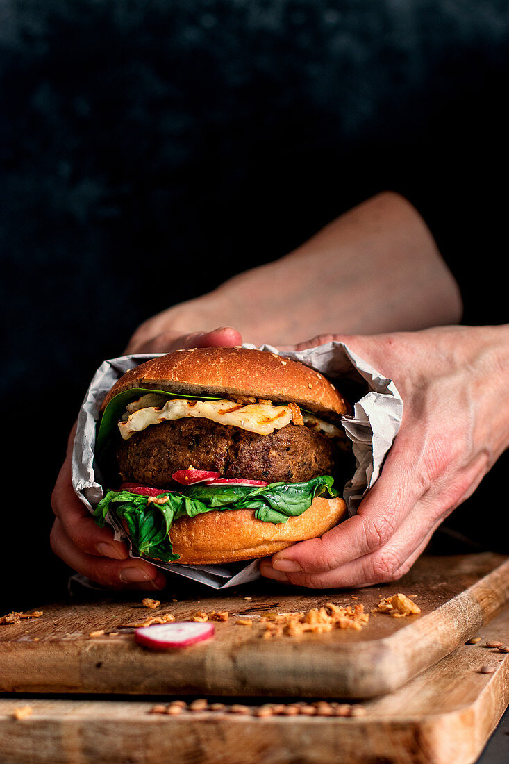 Hands holding a vegan lentil burger