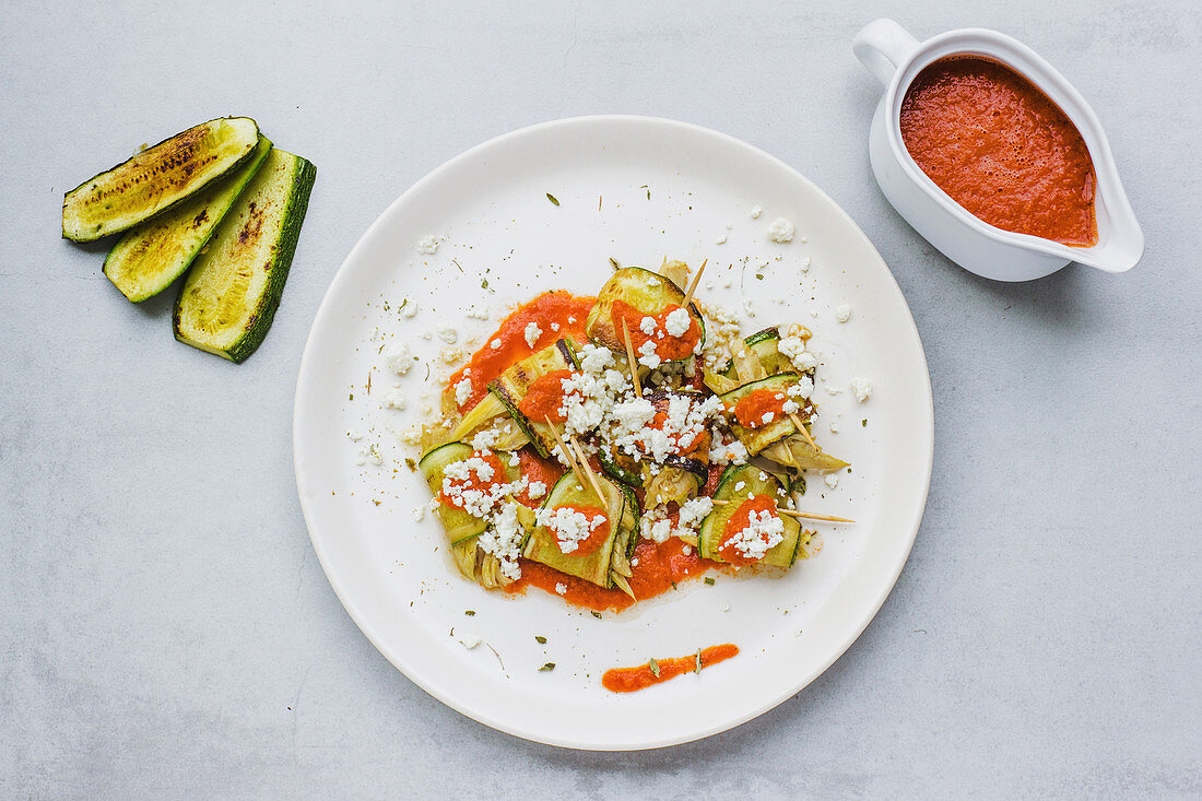 Fried zucchini with goat cheese and tomato sauce on gray surface