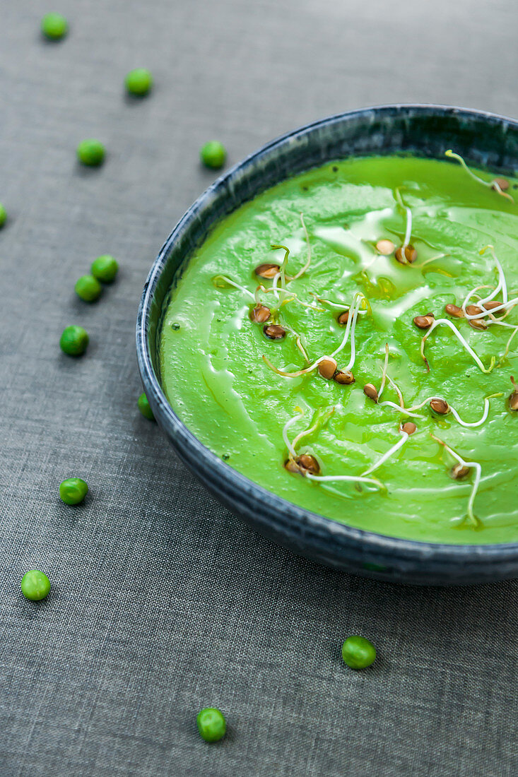 Bowl of freshly made puree of green peas topped with oil and sprouts