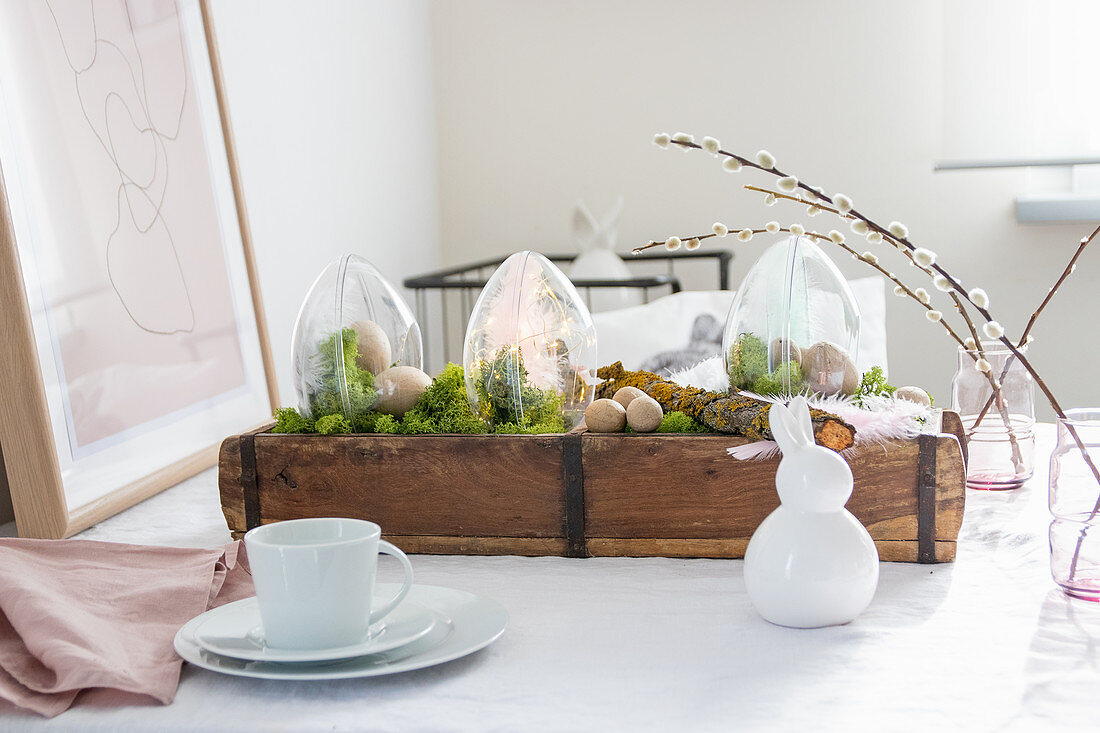 Osterdekoration mit transparenten Kunststoff-Eiern und Moos in Holzkästchen