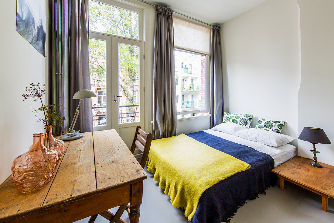 Vase on wooden table and double bed in bedroom