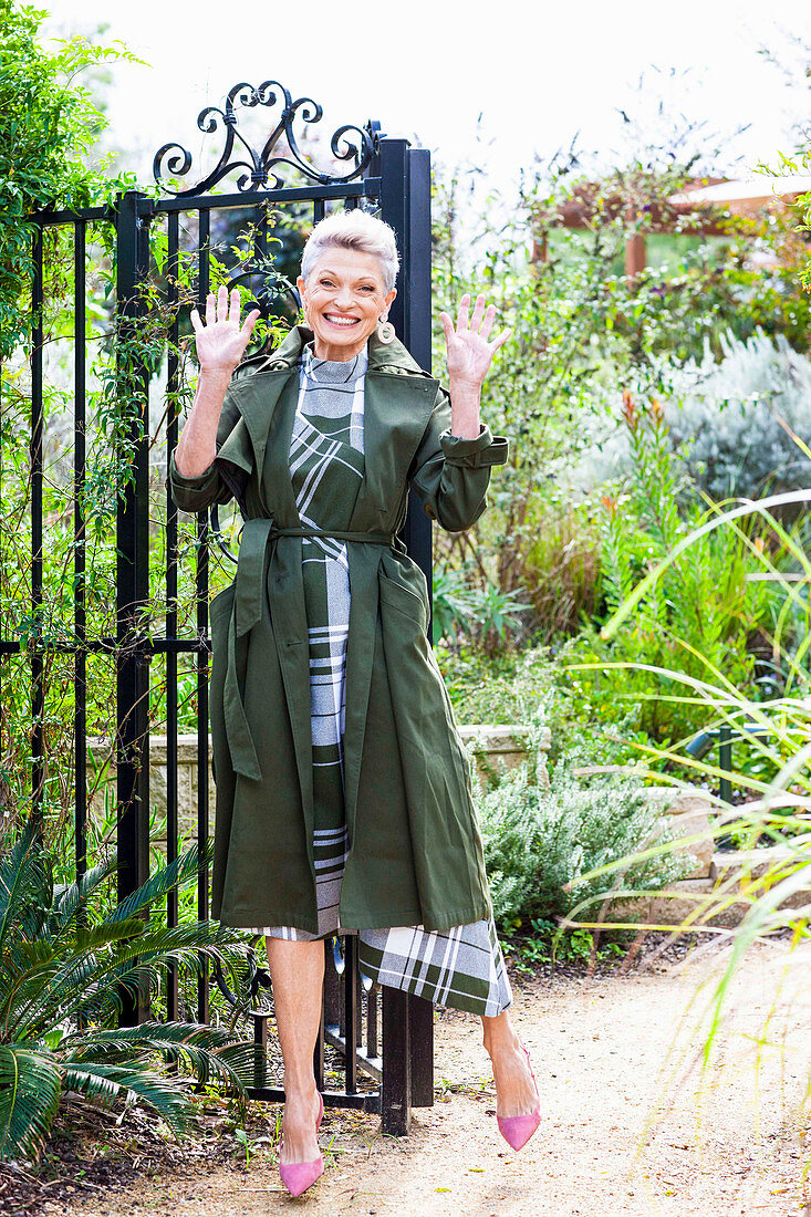 A grey-haired woman wearing a green checked dress and a green coat