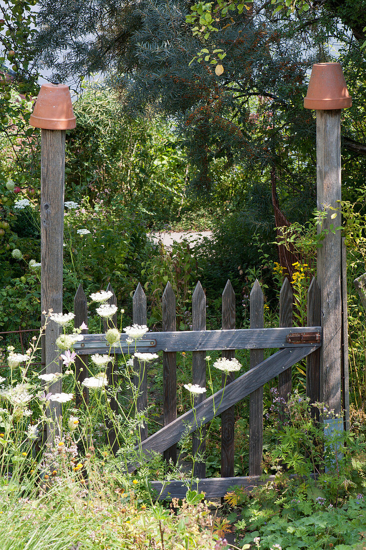 Wooden garden gate with clay pots on the goal post