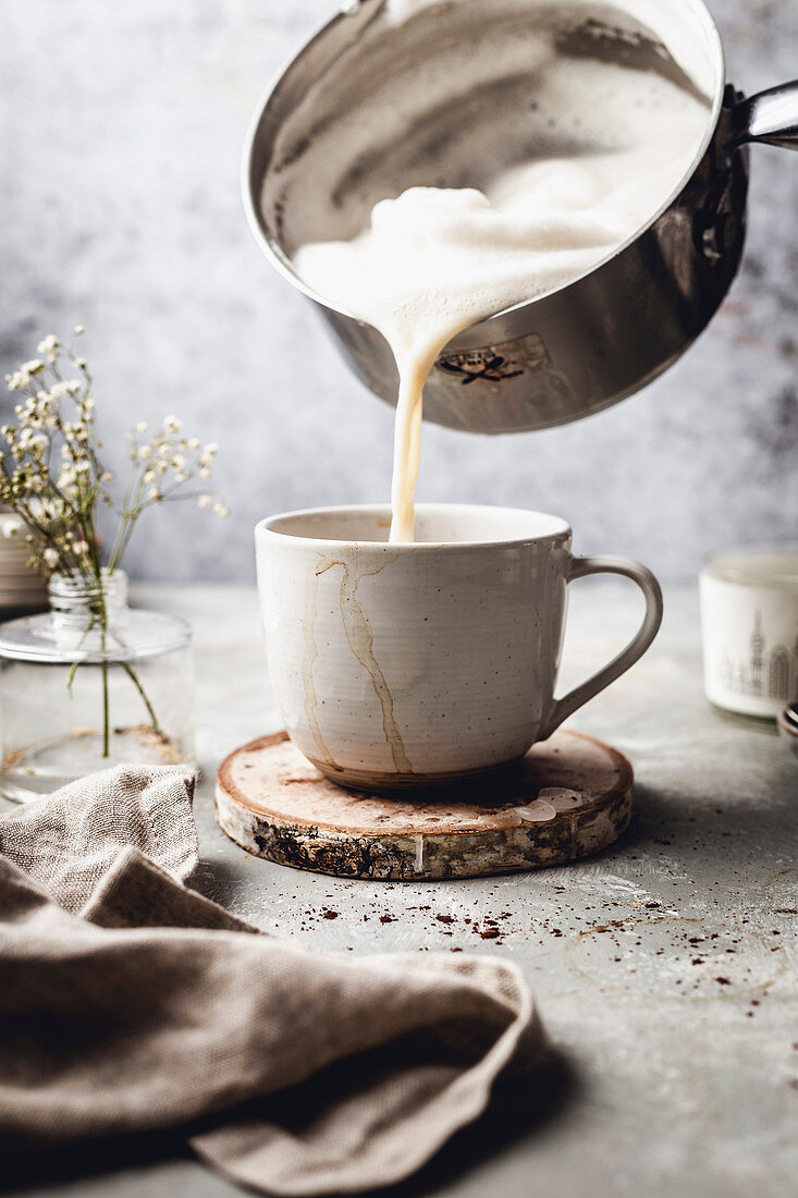 Mandel Latte zubereiten: Milchschaum zum Kaffee geben