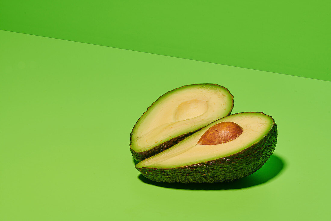 Halbierte Avocado auf hellgrünem Untergrund