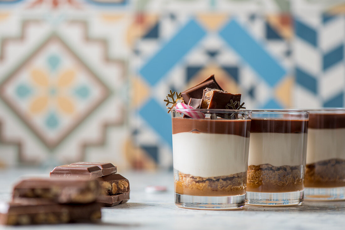 Yummy vanilla and chocolate dessert in glass cup decorated with Christmas items