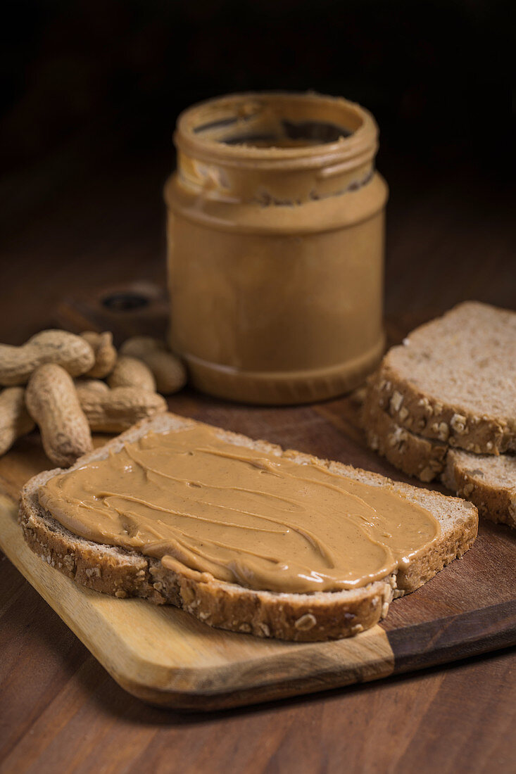 Eine Scheibe Brot mit Erdnussbutter auf Holzbrett