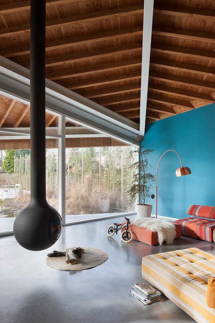 Hanging fireplace in modern living room with blue wall and wooden beamed ceiling