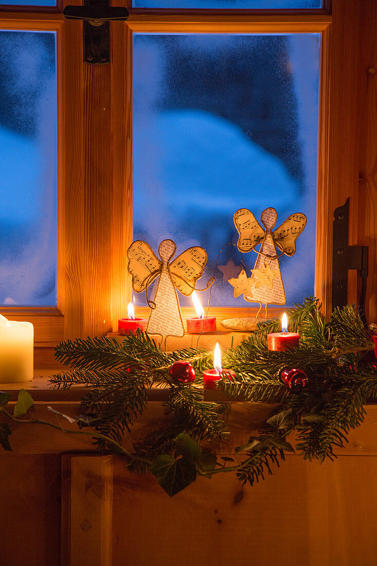 Engel aus Notenpapier und Kerzendeko am ländlichen Fenster