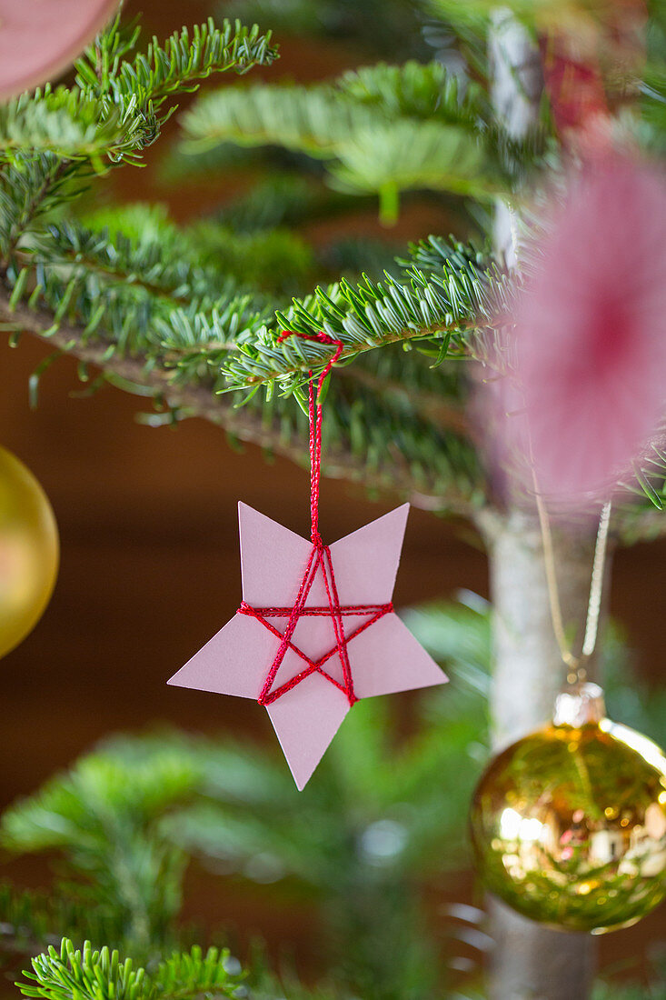 Selbstgemachter Christbaumanhänger aus mit Garn umwickeltem Papier