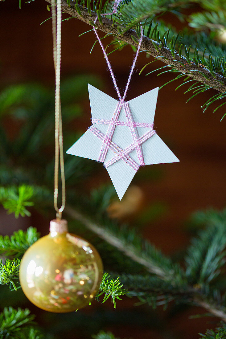 Selbstgemachter Christbaumanhänger aus mit Garn umwickeltem Papier