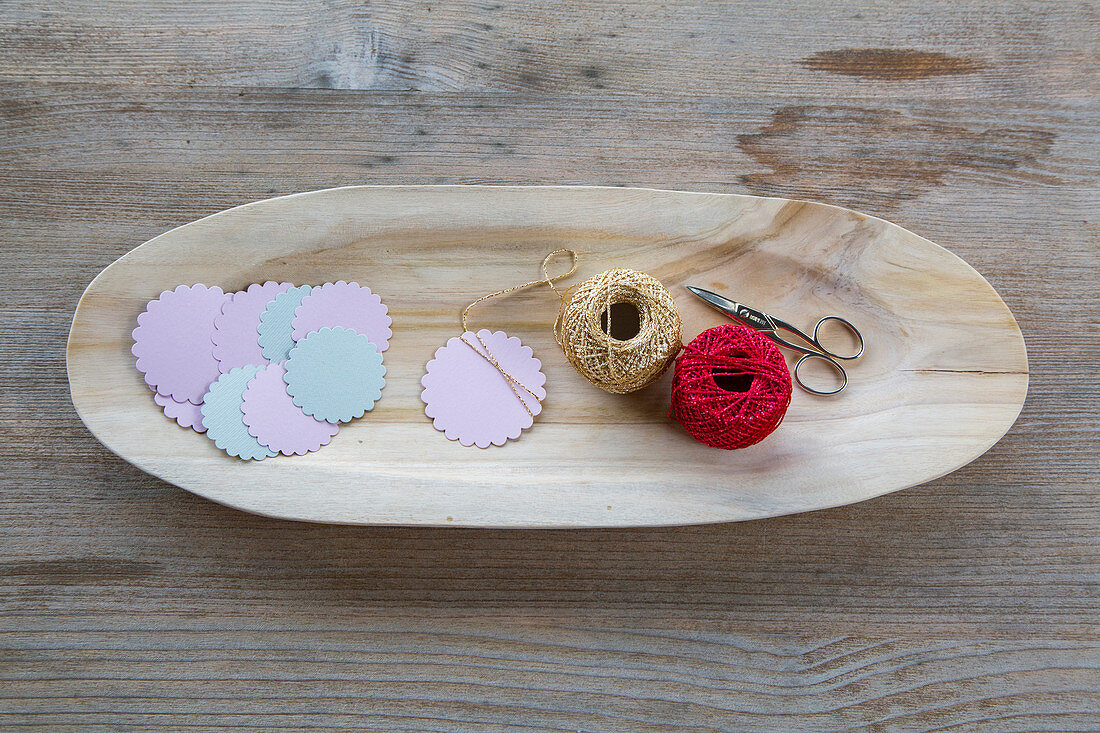 Punched paper, scissors and reels of thread in wooden dish