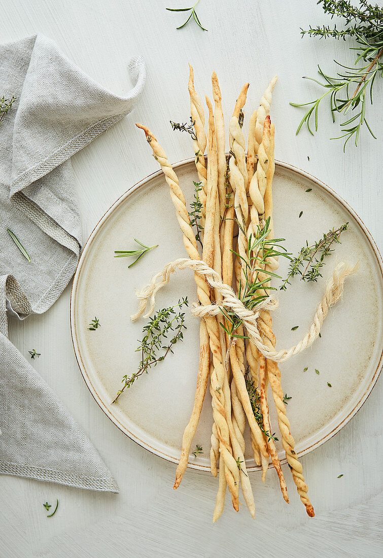 Grissini with rosemary and thyme on a light background