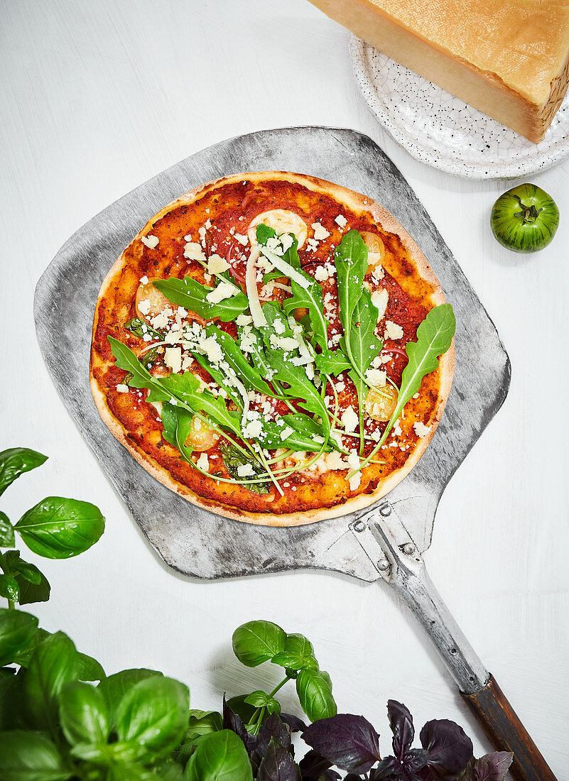 Pizza with arugula and parmesan on a pizza shovel