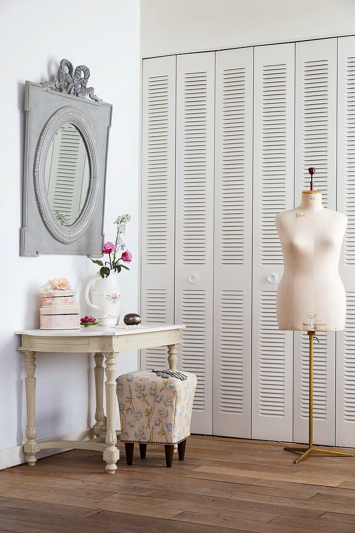 Console table and tailors' dummy in front of fitted cupboards