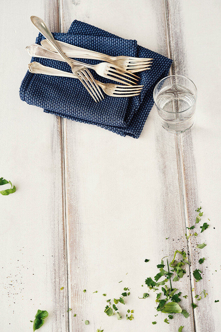 Herbs, napkin, fork and a glass of water