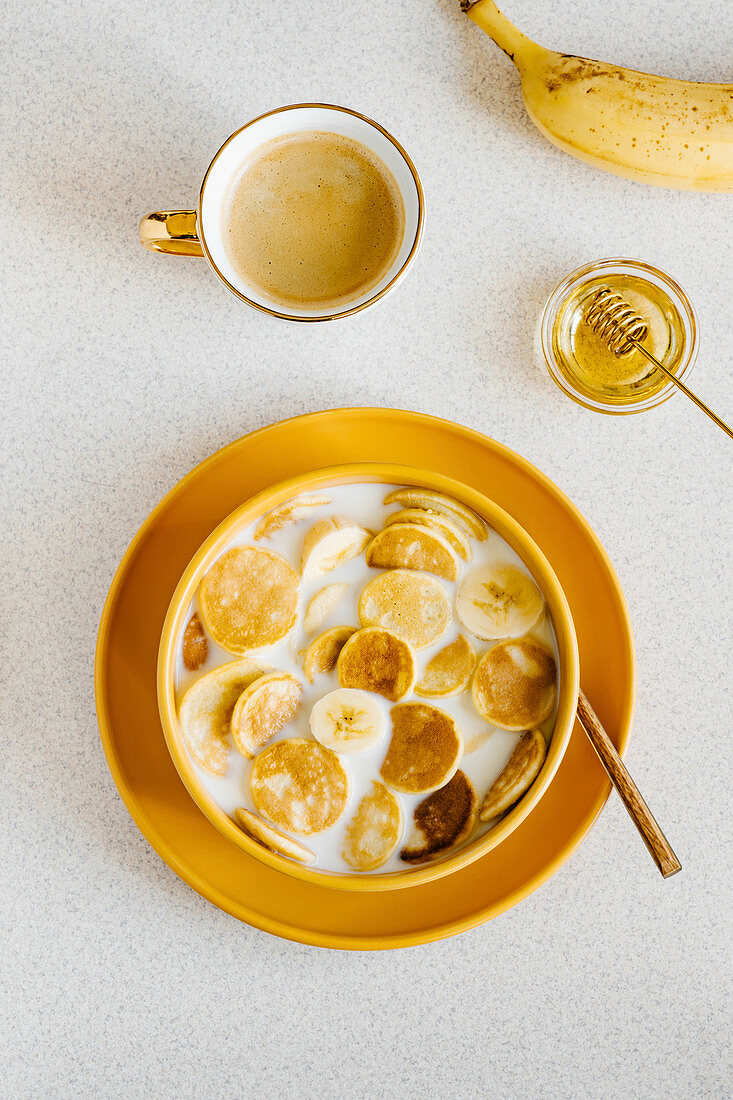 Pancake cereal in a bowl of milk with banana and honey