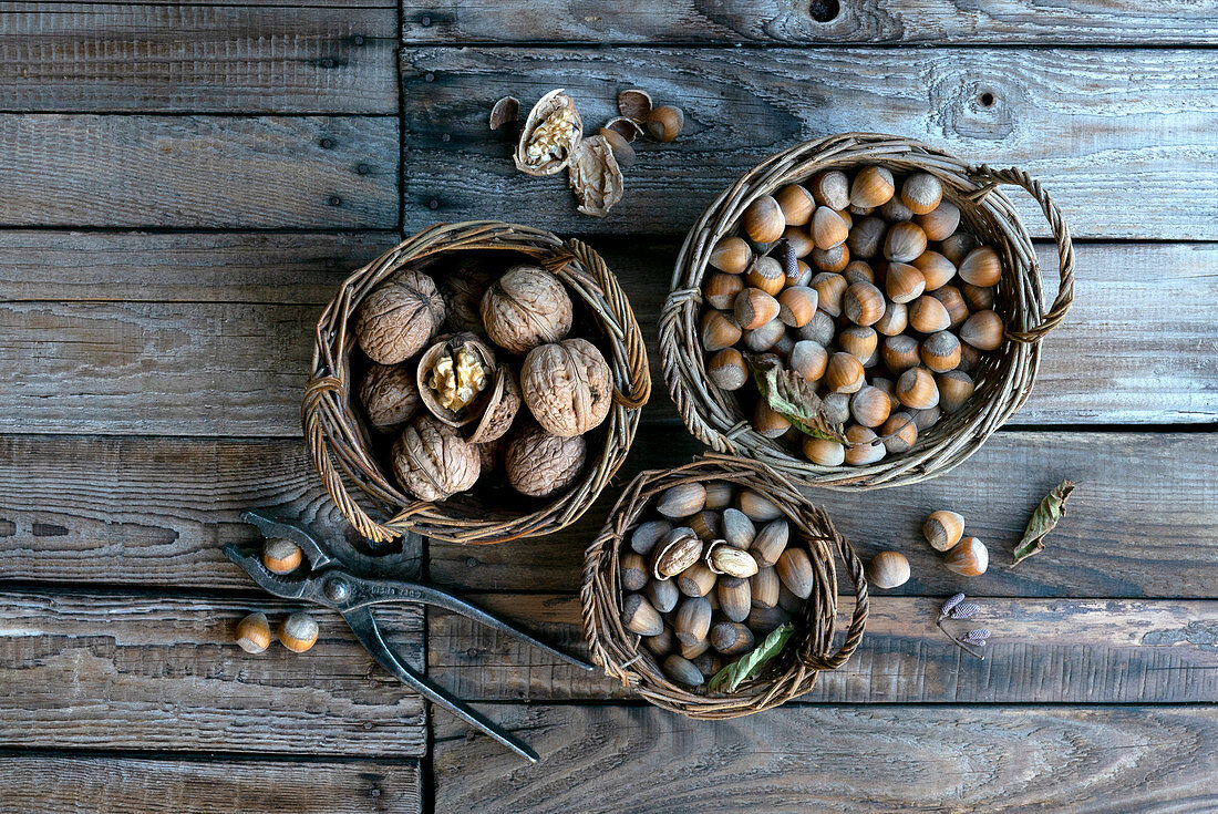 Verschiedene Nüsse in Weidenkörben auf Holztisch